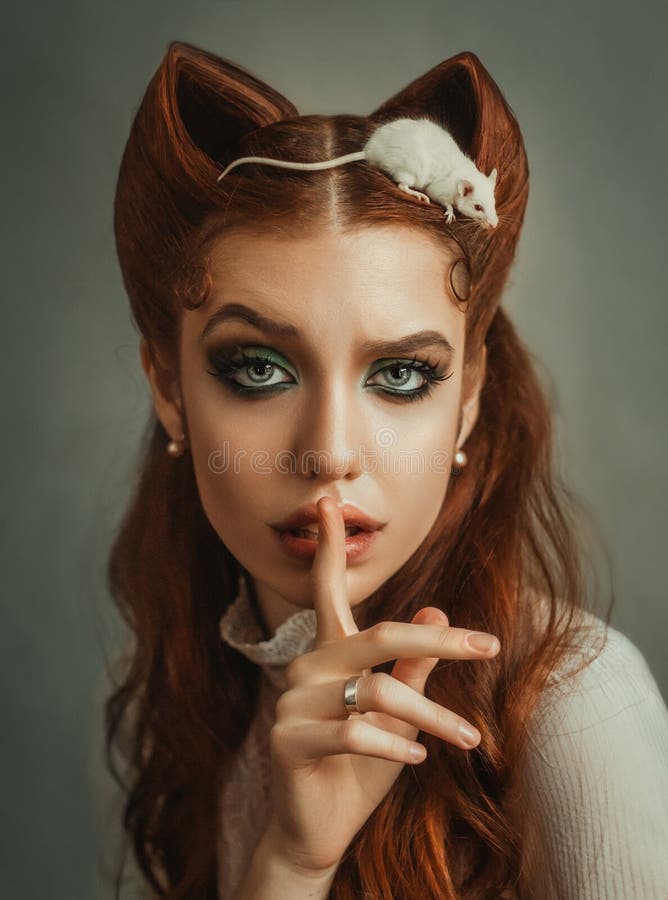 有红色头发和鲜绿色的构成的猫耳朵的逗人喜爱的夫人,女孩请求沈默投入手指到嘴唇,少许白色 免版税库存照片 有红色头发和鲜绿色的构成的猫耳朵的逗人喜爱的夫人,女孩请求沈默投入手指到嘴唇,少许白色 免版税库存照片